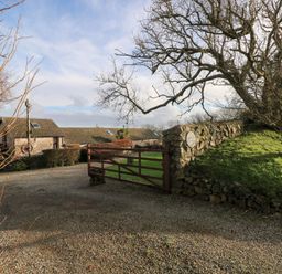 A gate leading to a gravel driveway with buildings and trees at 8 Rogeston Cottages Haverfordwest