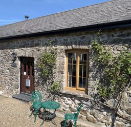 A door and window on a stone wall with a table and chairs at 8 Rogeston Cottages Haverfordwest