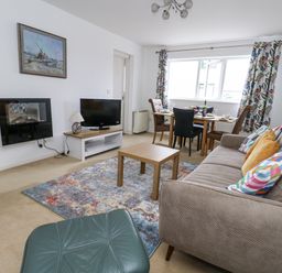 A living room with a sofa, television, and dining area at Flat 13, Chesil House, Bridport