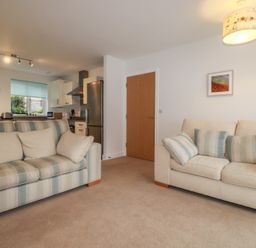 A living room with two sofas and a kitchen area visible at 13 Clock Tower Court in Charlestown