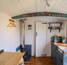 A small kitchen with wood stove and wooden table at Oak Shepherd Hut in Monkton Wyld near Charmouth