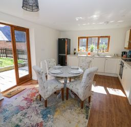 A kitchen with a round dining table set for four and floral upholstered chairs at Little Barn in Dodwell near Stratford-Upon-Avon