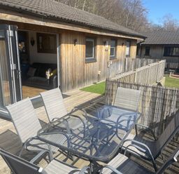 An outdoor patio with a table and chairs at Woodburn Lodge in Otterburn