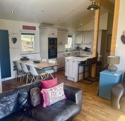 A kitchen and dining area with a table and chairs at Woodburn Lodge Otterburn