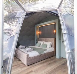 A bedroom inside a transparent dome structure with a bed and folded towels at Number 1 Dome in Derrybeg County Donegal