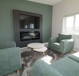 A living room with green sofas coffee tables and a wall-mounted tv at Number 2 Villa - The View in Derrybeg County Donegal