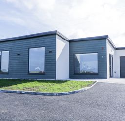 A modern single-story house with large windows a driveway and a garage at Number 5 Villa - The View in Derrybeg County Donegal