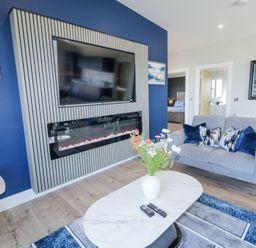 A living room with a grey sofa a white marble coffee table with a vase of flowers a wall mounted television above a modern fireplace at Number 5 Villa - The View in Derrybeg County Donegal