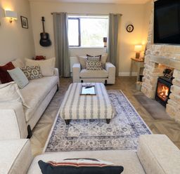 A living room with furniture and a fireplace at Yew Tree Cottage in Mealsgate near Ireby