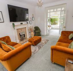 A living room with orange sofas and a television at Burry House Llanmorlais