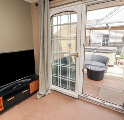 A living room with a television and a door leading to outdoor seating at 3 Hawk Place Moresby Parks near Whitehaven
