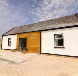 A house exterior with a wooden front door and planters at Teach Ti in Miltown Malbay