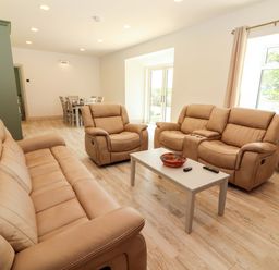 A living room with beige furniture and a table at Teach Ti in Miltown Malbay
