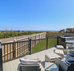 An outdoor seating area with a hot tub overlooking the sea at Life's a Beach Bacton