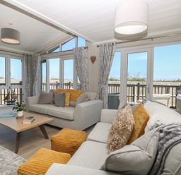 A living room with seating and large windows at Life's a Beach in Bacton