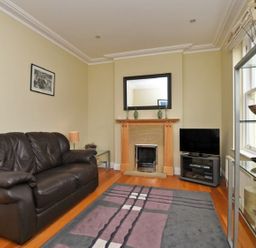 A living room with a leather sofa fireplace and television at Churchside in Alnwick