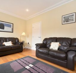 A living room with two brown leather sofas a lamp and framed pictures on the wall at Churchside in Alnwick