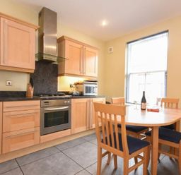 A kitchen with wooden cabinets and a dining table with four chairs at Churchside in Alnwick