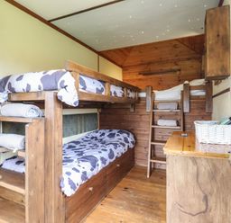 A small wooden bedroom with bunk beds and a dresser with a basket at Buttercup Cow Shed 3 in Easton near Campsea Ashe