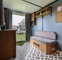A small room with a bench seat cushions shelves with plants and a corkboard at Dozy Dotty Cow Shed 4 Easton near Campsea Ashe