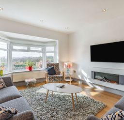 A living room with sofas armchair coffee table wall mounted TV and electric fireplace at Bryn Derw in Caernarfon