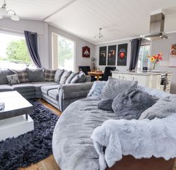 A living room with grey sofas a dining table kitchen island and wall art at 155 Woodland Hall Lyons in Ruthin