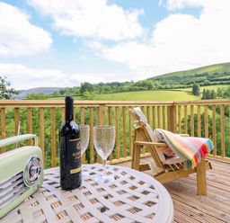 A table with wine, glasses, and a radio on a deck at The Owlet in Dolwen near Llanidloes
