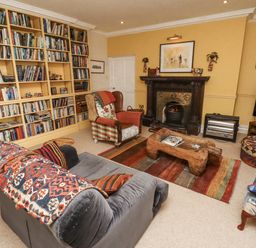 A living room with a fireplace and bookshelf at Elford Farmhouse in Seahouses