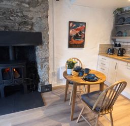 A kitchen with a table and chairs near a wood stove at 4 Old Tanrhiw Beddgelert