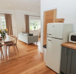 A kitchen with a refrigerator and a table at The Lodge in Bridgend