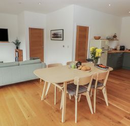 An open plan living area with a dining table and kitchen at The Lodge in Bridgend
