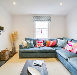 A living room with a sectional sofa and a TV at Church Hill House in Port Isaac
