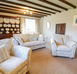 A living room with sofas and cushions and a wooden cabinet with plates at Dwynant in Bontddu near Dolgellau