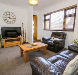A living room with brown leather sofas wooden coffee table flat screen TV and wooden blinds at Gilfach Bach in Dolgellau