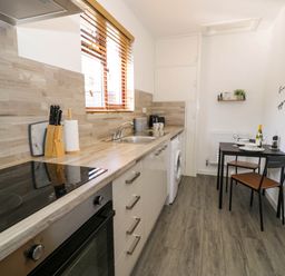 A kitchen with a stove oven sink washing machine small dining table and two chairs at Gilfach Bach in Dolgellau