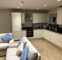 A kitchen with cabinets, a stove, and a sofa at Pen Y Ffrith Lodge in Prestatyn