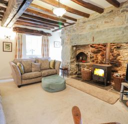 A living room with stone fireplace wood burner two sofas and a television at Ty Glan Yr Afon in Bontddu near Dolgellau
