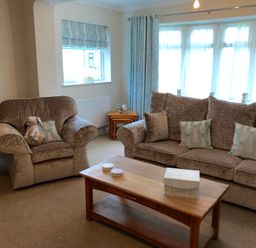 A living room with a sofa armchair wooden coffee table and curtains at Pen Y Frith Bungalow in Prestatyn