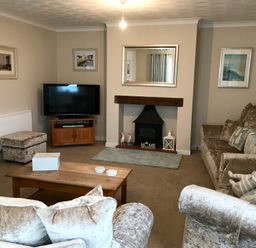 A living room with sofas a coffee table a television and a fireplace at Pen Y Frith Bungalow in Prestatyn