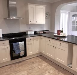 A kitchen with white cabinets black countertop and kitchen appliances at Pen Y Frith Bungalow in Prestatyn