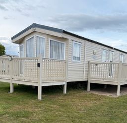 A mobile home with a deck and steps at Caravan 607 in Clacton-On-Sea