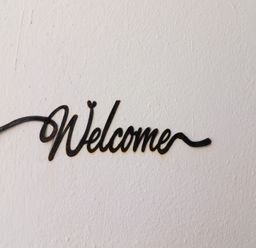 A black metal welcome sign mounted on a white textured wall at Killelton Cottage in Camp County Kerry