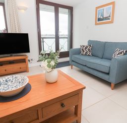 A living room with a sofa and tv stand at Tobys Quay in Falmouth