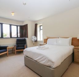 A bedroom with a bed and two chairs at Bedroom 10 in Littlehampton
