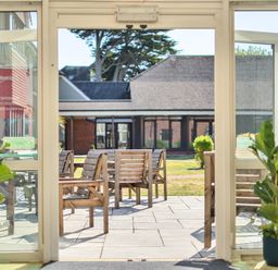 An outdoor area with chairs and tables visible through a glass door at Marine Court First-floor Double Bedroom with Wet Room Littlehampton