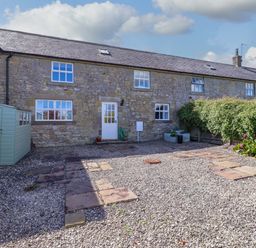 An outdoor area with a stone wall and gravel at 3 Christon Bank Mews in Christon Bank