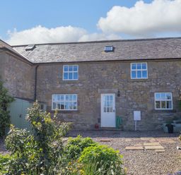 A stone house with a garden and pathway at 3 Christon Bank Mews in Christon Bank