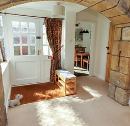 A hallway with a bench and door at 3 Christon Bank Mews in Christon Bank
