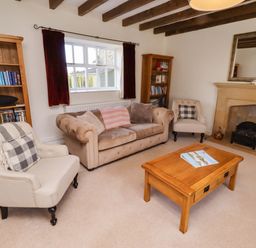 A living room with a bookshelf and a coffee table at 3 Christon Bank Mews in Christon Bank