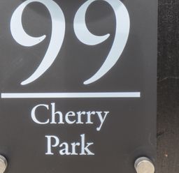 A black house number sign with the number 99 and the text Cherry Park at 99 Cherry Park in Chapel St Leonards